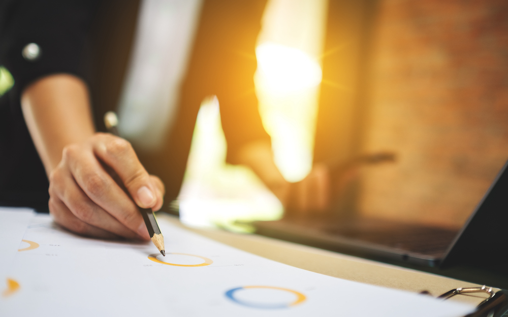 A businesswoman writing and working on business financial data and laptop computer on the table in office